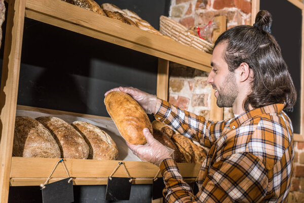 Side view of seller taking freshly baked bread in hands