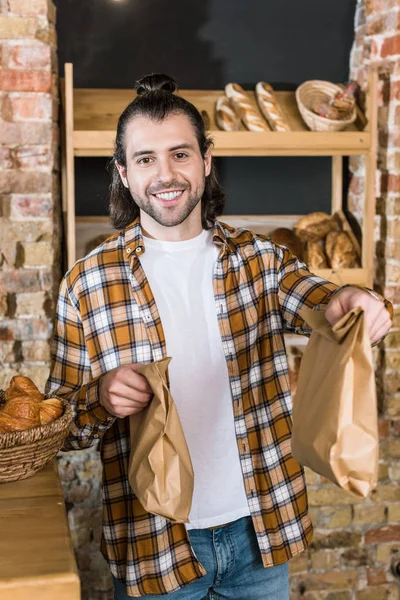 Lachende Mannelijke Verkoper Houden Papieren Zakken Bakkerij — Gratis stockfoto