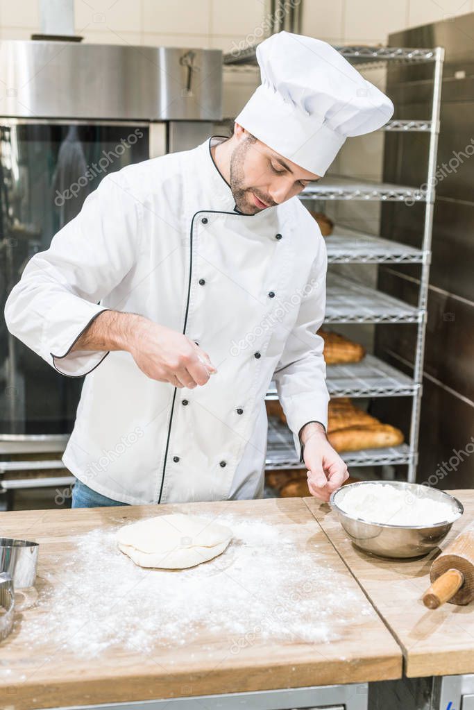 handsome baker cooking bread at workplace in bakery