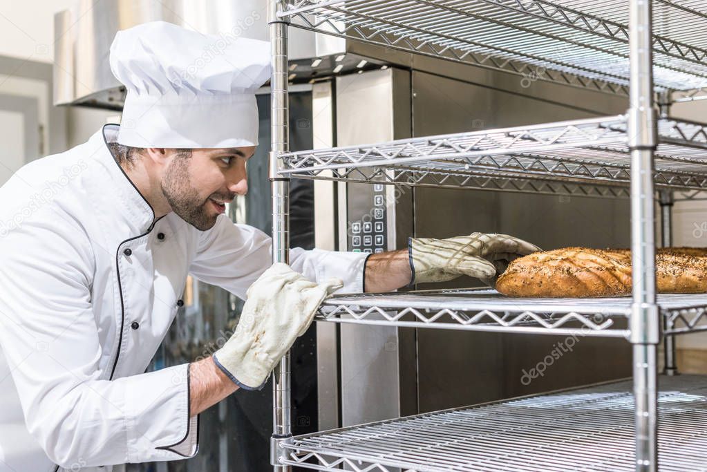 Side view of baker in gloves taking bread 
