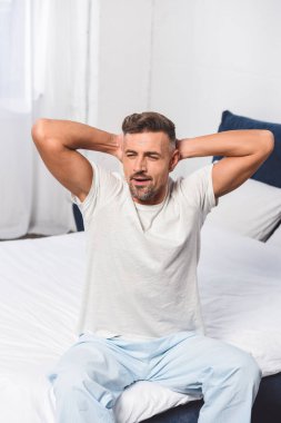 Sleepy man stretching and yawning on bed  clipart