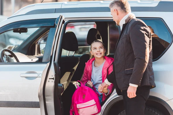 Father helping daughter getting out of car