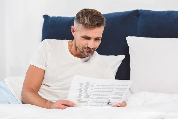 ハンサムな男のベッドで新聞を読む  — 無料ストックフォト