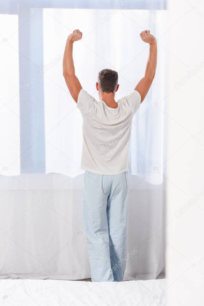 Back view of man stretching in room