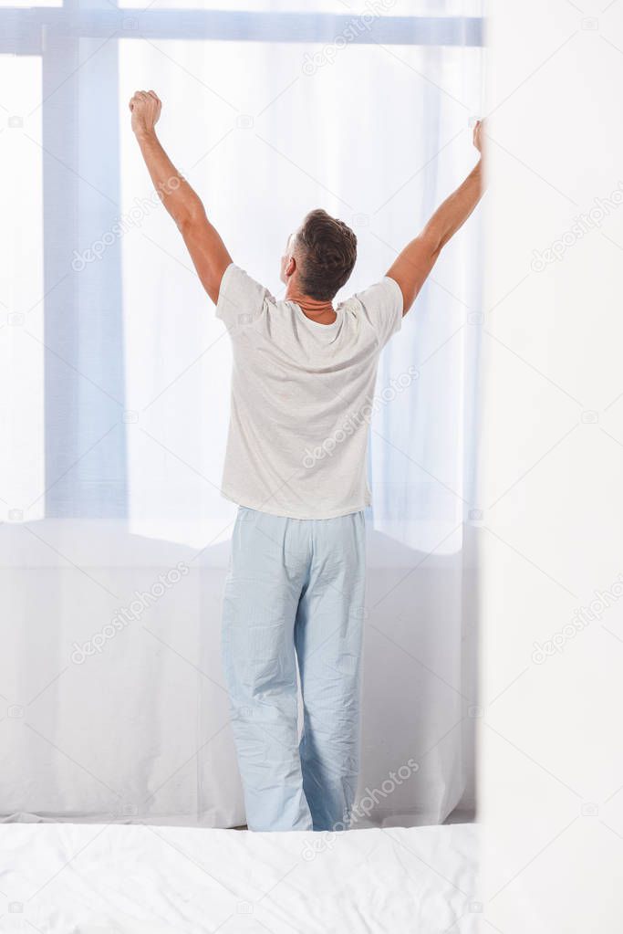 Back view of man standing in pyjamas in room 