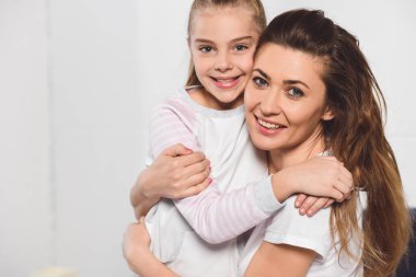 Anne ve kızı sarılma ve yatak odasında gülümseyen
