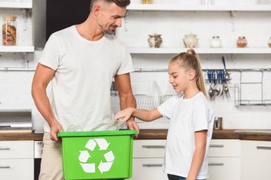 Baba ve kızı birlikte yeşil geri dönüşüm kutusunu boş plastik şişe koyarak