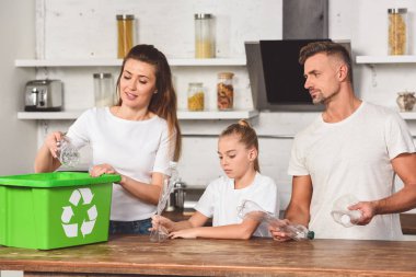 mutfak at aile ayakta ve boş plastik şişe geri dönüşüm kutusuna koyarak 