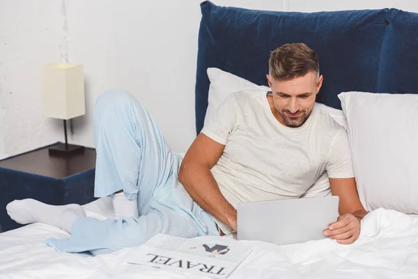 Όμορφος Άνδρας Χρησιμοποιώντας Φορητό Υπολογιστή Και Ξαπλωμένη Στο Κρεβάτι — Φωτογραφία Αρχείου