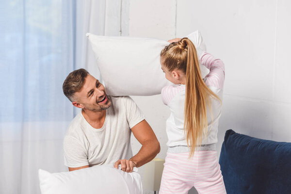 Father and daughter having pillow fight at home