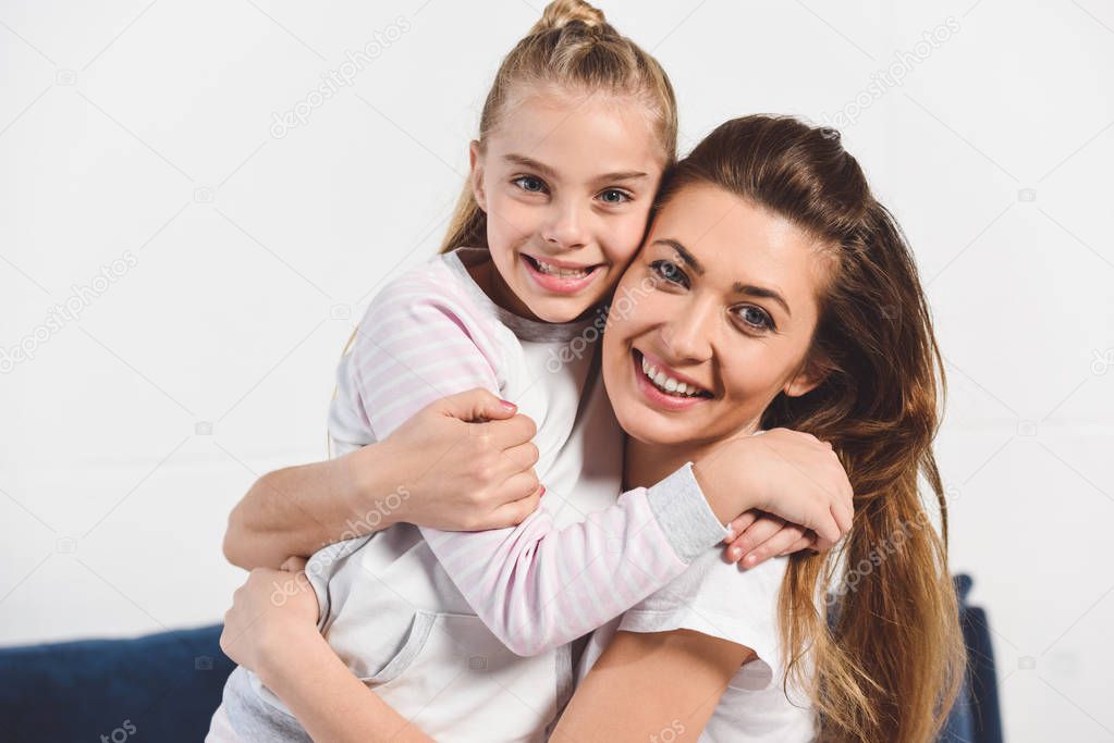 Mom and daughter embracing and smiling at home 