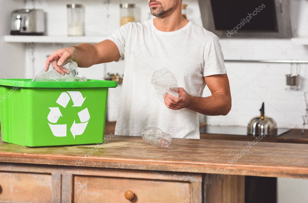 cropped vie of man putting plastic bottles in green recycle box