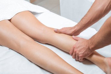 cropped view of man massaging woman legs in spa center clipart