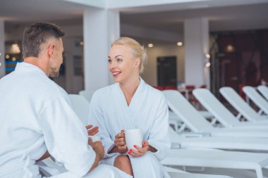 gülümseyen çift güverte sandalyeleri Spa beyaz cups ile oturan