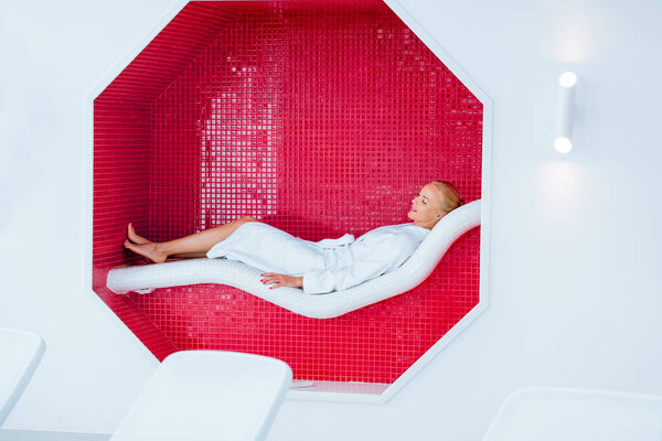 blonde woman lying on white deck chair in mosaic octagon