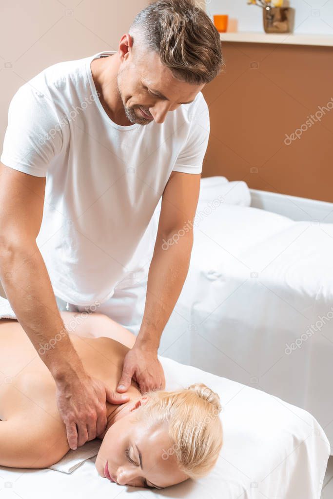 Handsome masseur doing neck massage to blonde woman