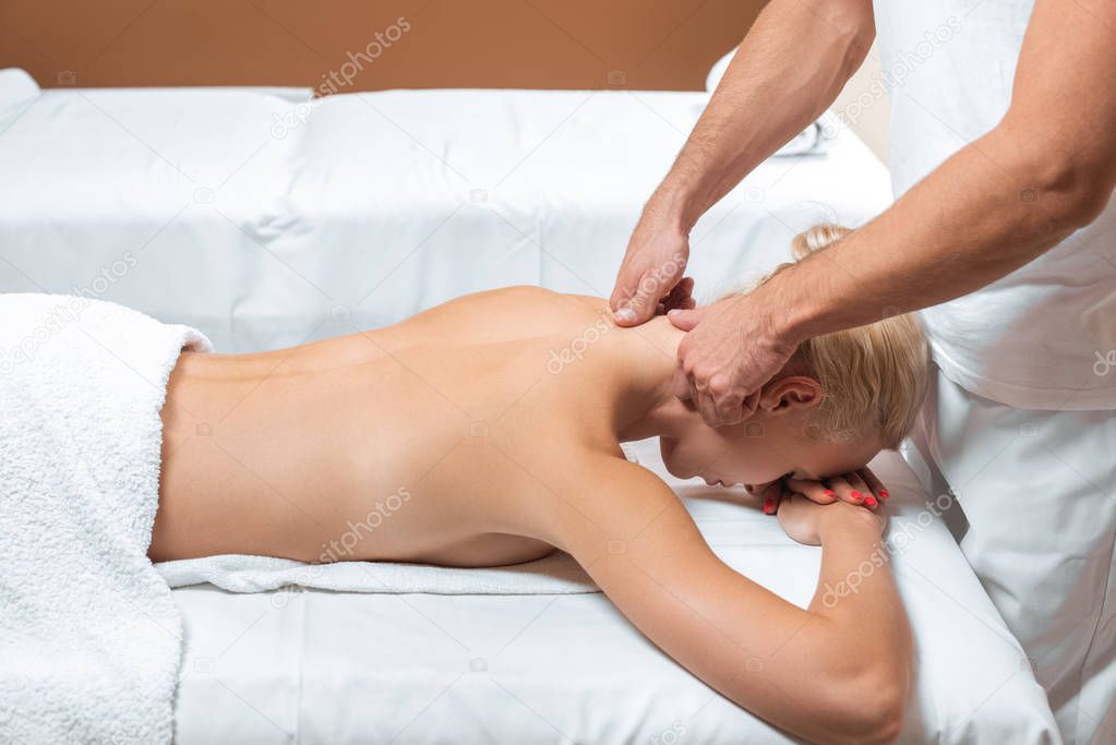 Male therapist doing neck massage to woman in beauty salon 