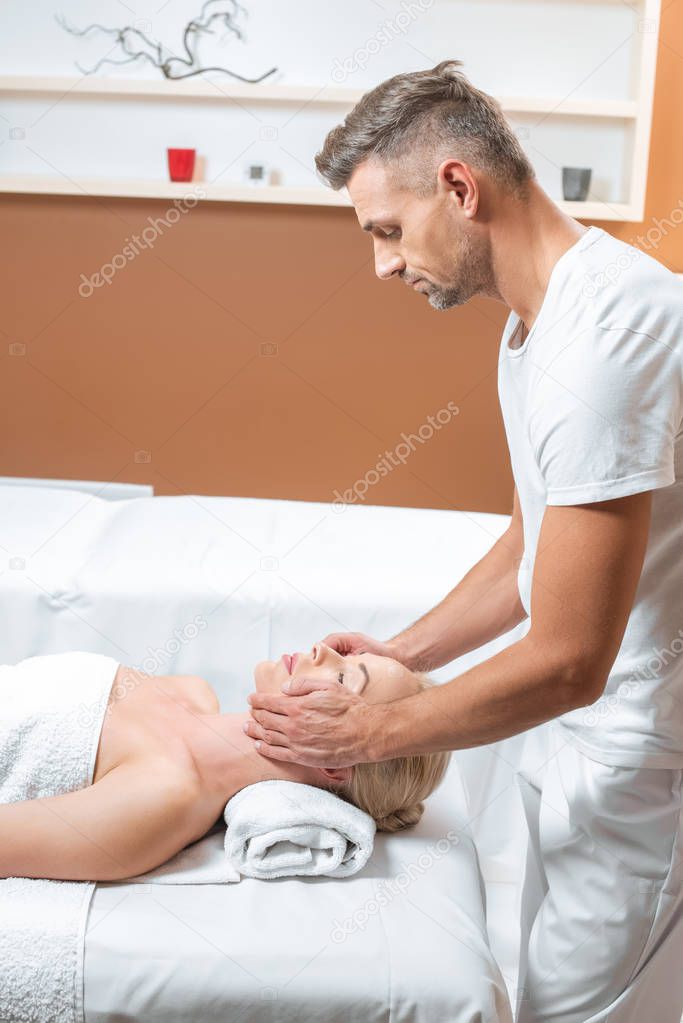 Male masseur doing face massage in spa salon 
