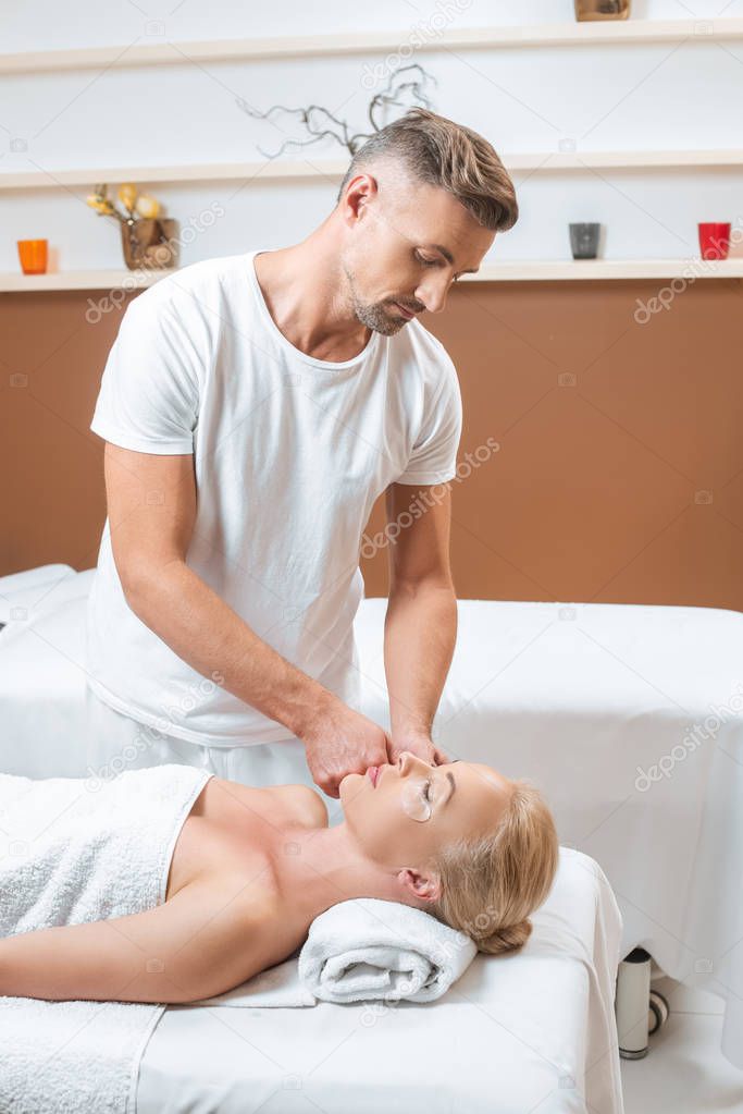 Handsome masseur applying eye patches to woman face 