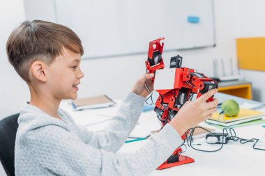 gülümseyen öğrenci sınıfta kırmızı el yapımı robot ile oynarken