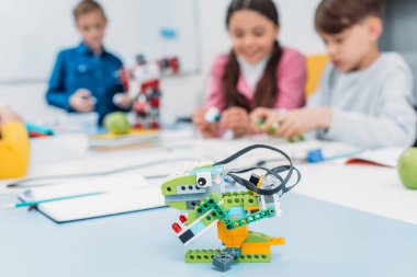 arka planda kök sınıf, okul ile masada çok renkli el yapımı robot