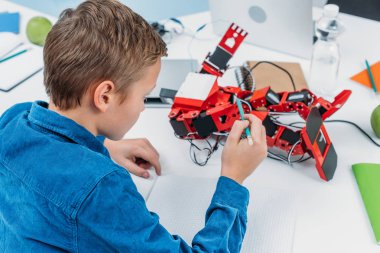 masada oturan ve el yapımı kalem kırmızı robot ile kök ders sırasında dokunmadan öğrenci