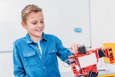 kök sınıfta kırmızı robot dokunmadan gülümseyen okul çocuğu
