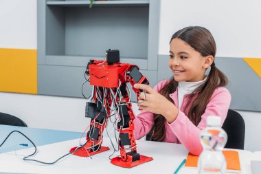gülümseyen ve robot modeli kök ders sırasında holding masadan, sevimli kız öğrenci  