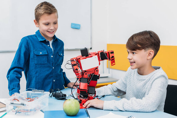 школьники, работающие над роботом на уроке робототехники STEM
