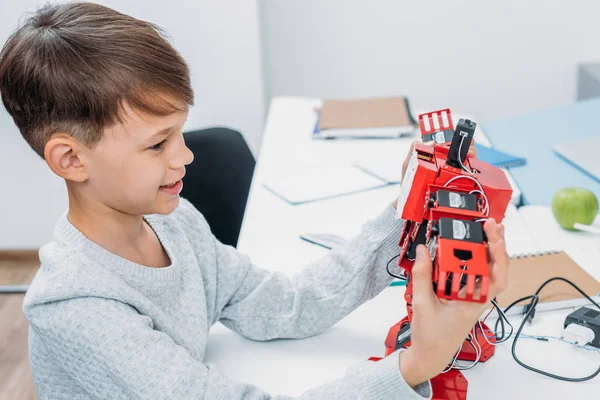 Sonriente Colegial Sosteniendo Robot Rojo Hecho Con Bloques Construcción Plástico — Foto de stock gratis