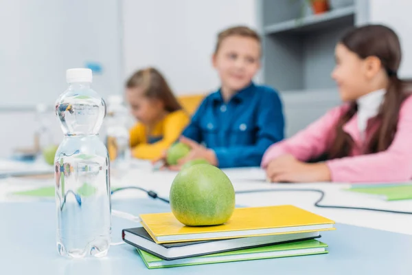 绿色成熟的苹果在笔记本和学童在后台在教室 — 图库照片