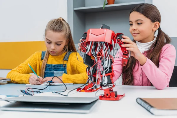 Alunas Escrevendo Notebook Tocando Robô Elétrico Vermelho Durante Lição Tronco — Fotografia de Stock