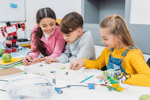 дети младшего школьного возраста, делающие робота с деталями в классе начального образования
