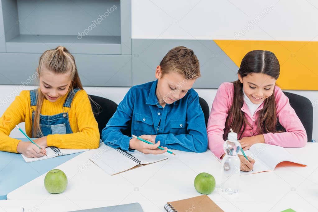 attentive pupils during lesson writing in notebooks