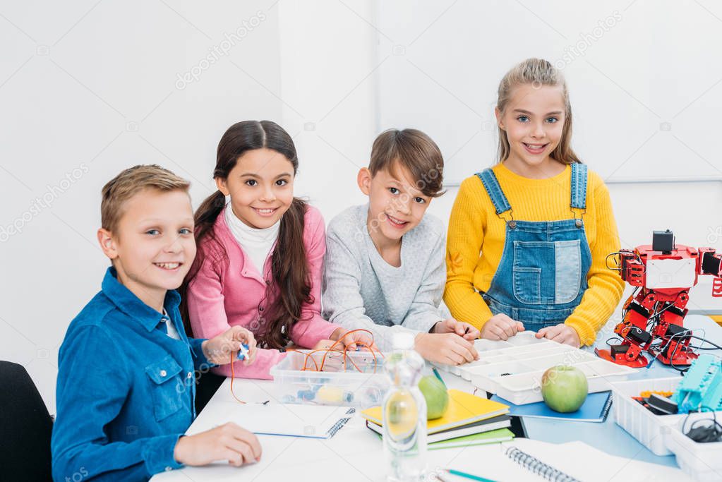 schoolchildren looking at camera and smiling at desk in stem education class