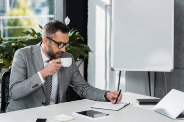 kahve içme ve işyerinde Not defterinizdeki yazma gözlük işadamı odaklı