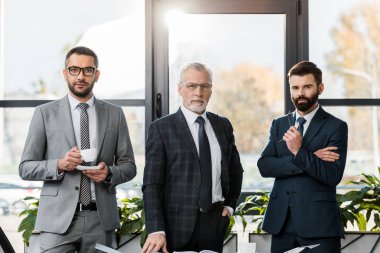 ayakta ve kamera Office bakarak elbiseli yakışıklı iş adamları