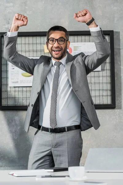 Fröhlicher Geschäftsmann Triumphiert Und Lächelt Die Kamera — kostenloses Stockfoto