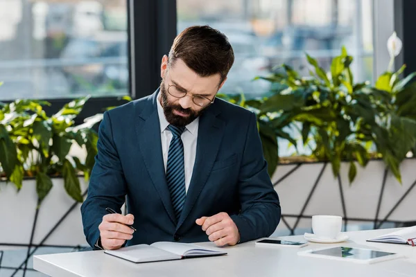 Fokuserad Skäggiga Affärsman Skriver Anteckningsboken Arbetsplatsen — Stockfoto