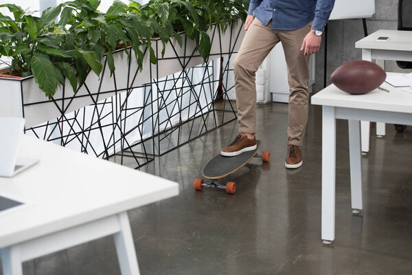 low section of businessman standing on skateboard in office