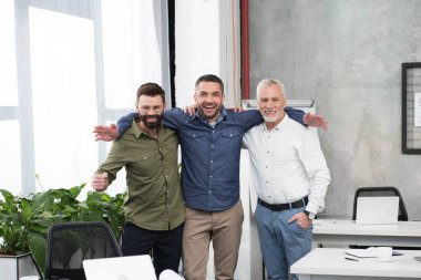 sarılma ve kamera Office bakarak gülümseyen yakışıklı iş adamları
