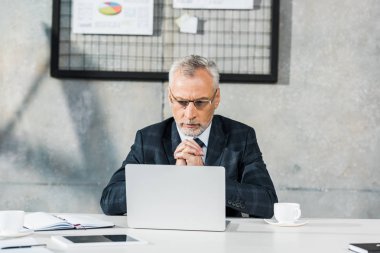 dalgın yakışıklı orta yaşlı işadamı office içinde laptop bakarak