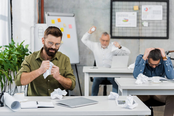 angry and sad businessmen tearing and throwing paper in office