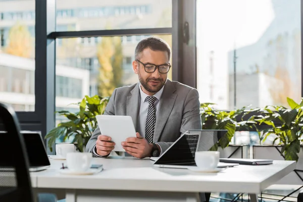 Alegre Guapo Hombre Negocios Sosteniendo Tableta Mirando Computadora Portátil Oficina — Foto de Stock