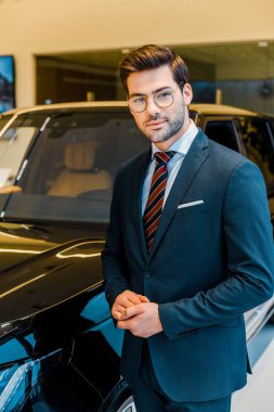 mutlu genç iş adamı araba showroom yakınındaki poz gözlük