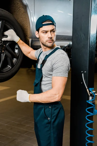 年轻的汽车机械师在汽车修理店站在汽车保护手套 — 免费的图库照片