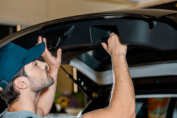 young auto mechanic checking car trunk at auto repair shop