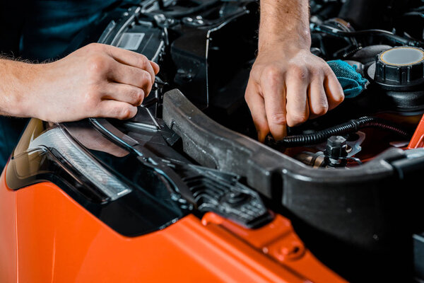 cropped shot of auto mechanic checking automobile