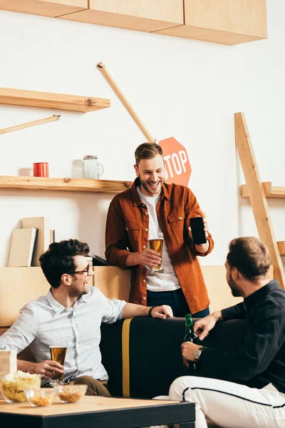 Cheerful Man Showing Smartphone Friends While Resting Cafe — Free Stock Photo