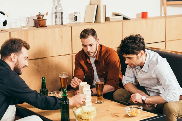 Amici Concentrati Giocando Blocchi Legno Gioco Tavolo Con Snack Birra — Foto Stock